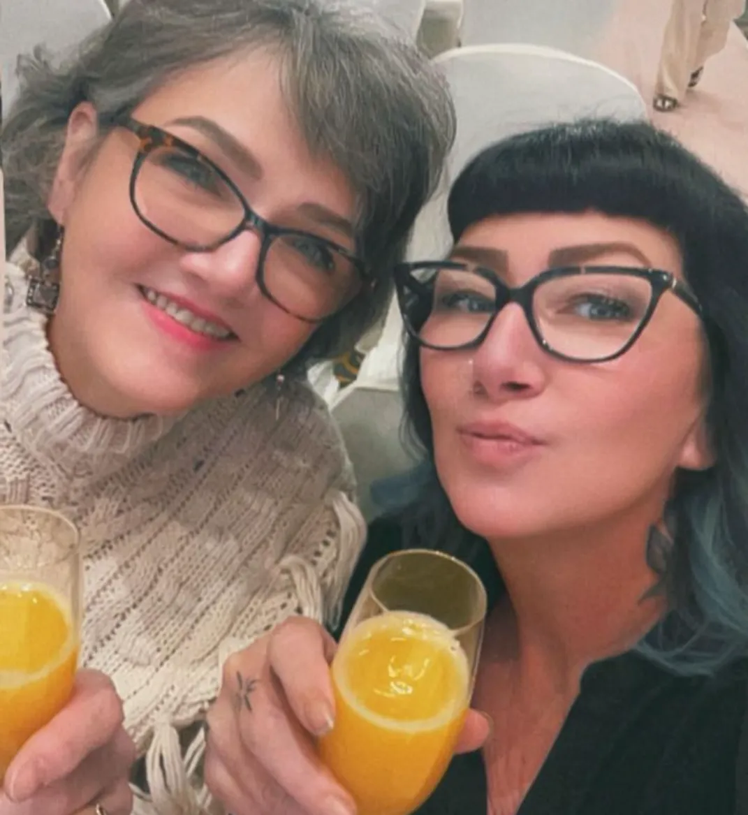 Sandra and Heather together, both in glasses: Sandra on the left in a cream knit, Heather on the right with dark micro-bangs and blue-tipped ends