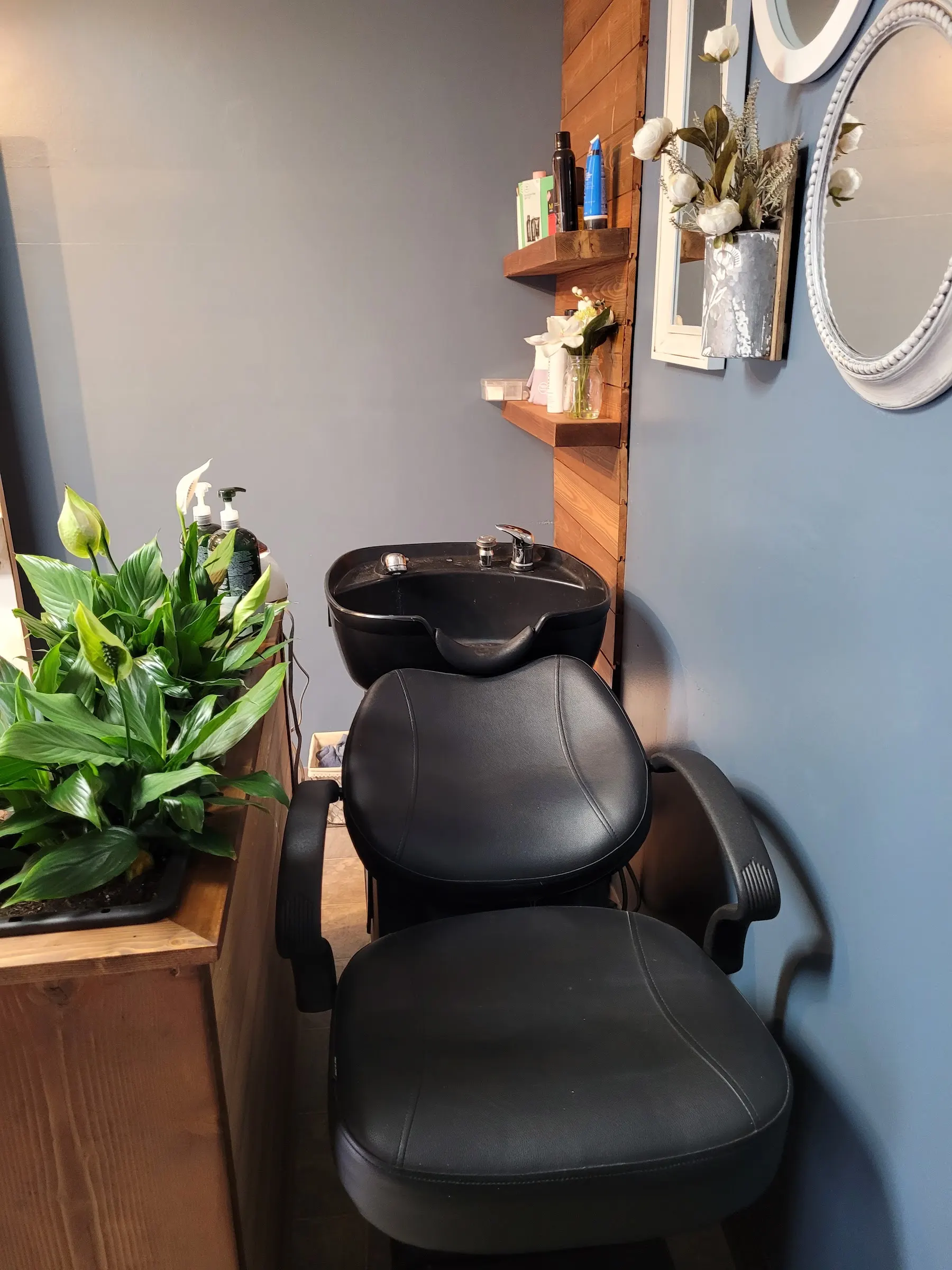 The wash station at Mane Obsession, a black basin chair against pine shelving and a slate wall