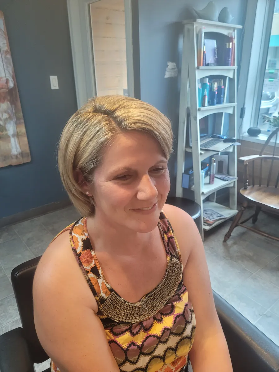 A client smiling in the chair with her new chin-length blonde bob